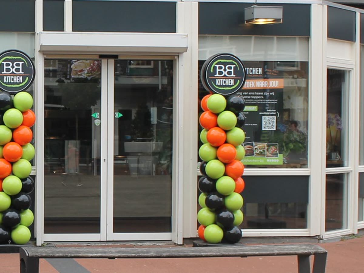 De ingang van BB Kitchen Huesmolen in winkelcentrum De Huesmolen, met het ronde BB Kitchen-bord naast de deur.